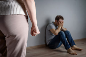 a woman standing over a man in a threatening pose