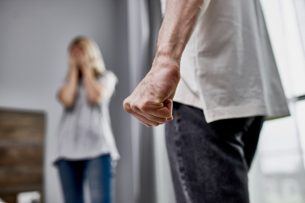 angry closed fist with a woman crying in the background