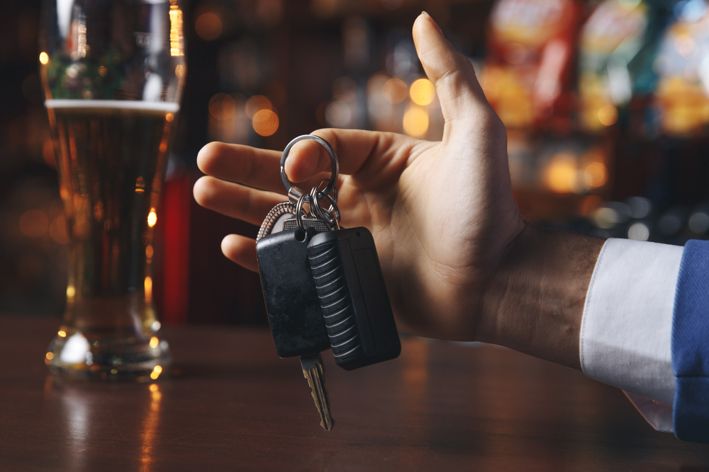 guy taking his keys near a drink on the bar