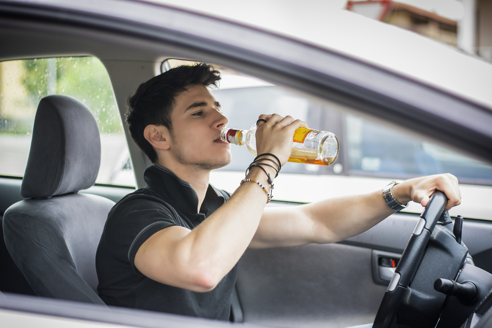 young guy drinking behind the wheel