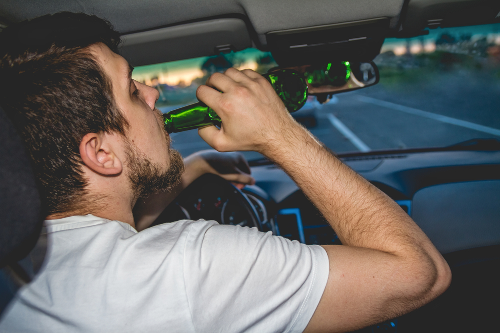 young man drinking behind the wheel