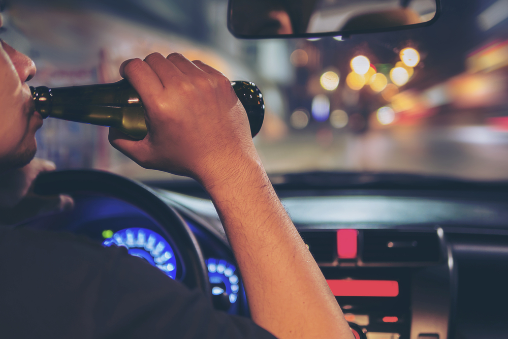 man driving with beer bottle in hand