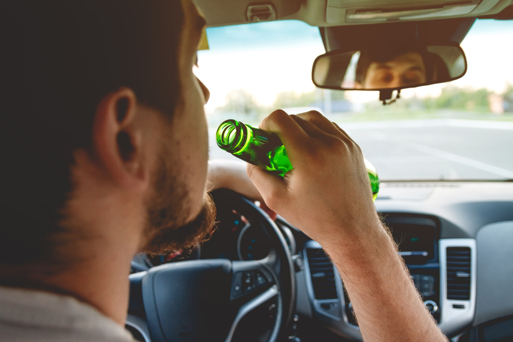 young man drinking behind the wheel