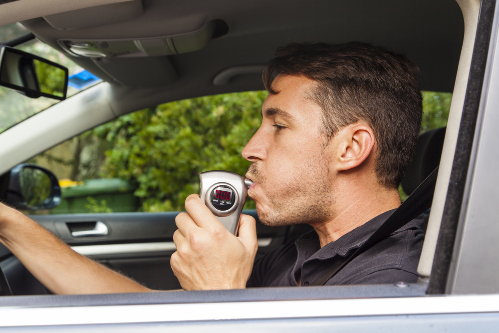 A man using a breathalyzer. Review the legal BAC limit for DWI charges in Texas with our team.
